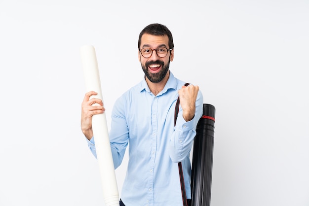 Joven arquitecto hombre con barba sobre blanco aislado celebrando una victoria en posición ganadora