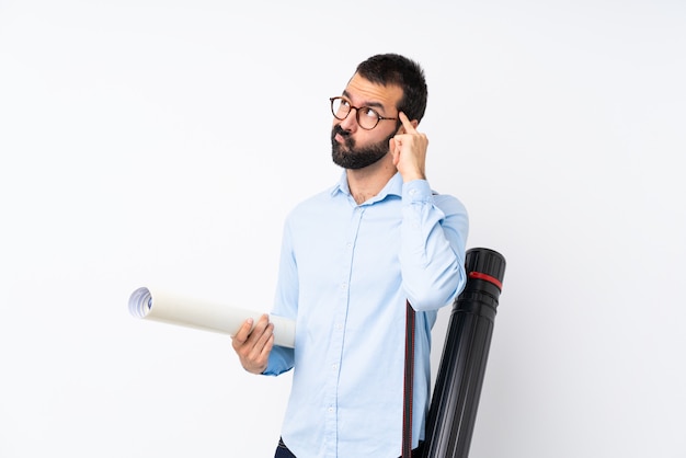 Joven arquitecto hombre con barba sobre pared blanca aislada con dudas y pensamiento