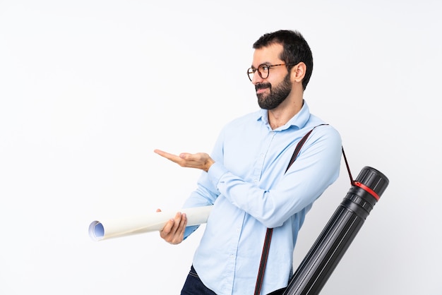 Joven arquitecto hombre con barba sobre una pared blanca aislada extendiendo las manos a un lado para invitar a venir