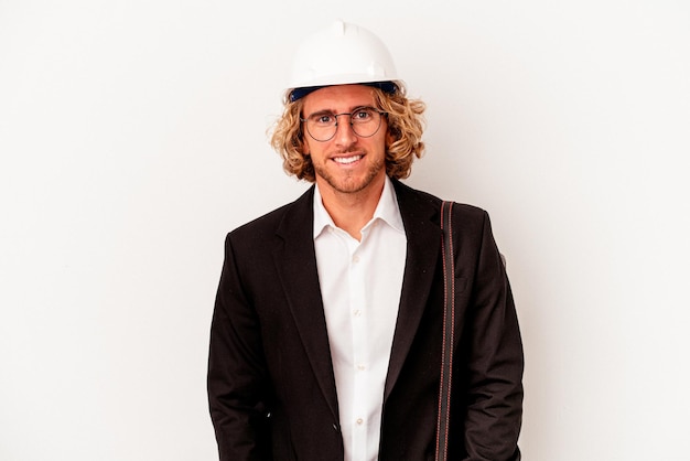 Joven arquitecto hombre caucásico con casco aislado sobre fondo blanco feliz, sonriente y alegre.