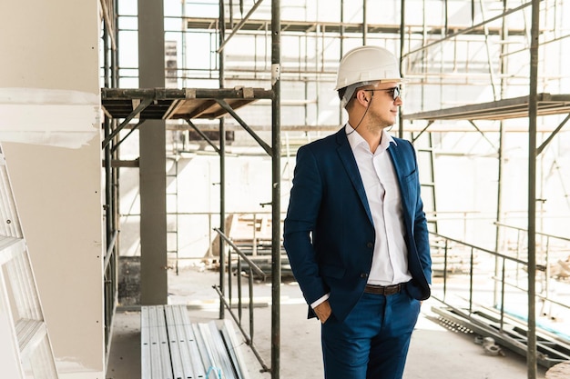 Joven arquitecto o empresario vistiendo traje formal y casco en un sitio en construcción