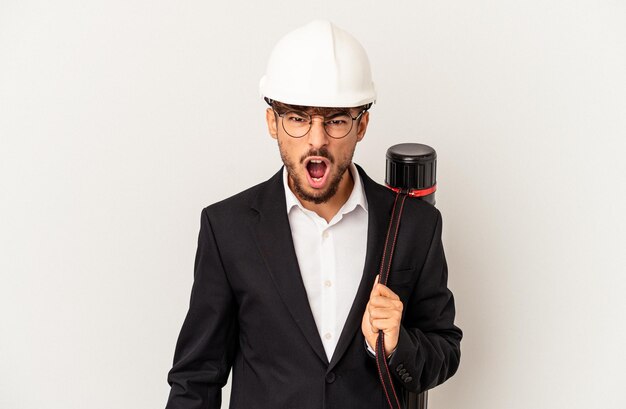 Joven arquitecto de raza mixta hombre que llevaba un casco aislado sobre fondo gris gritando muy enojado y agresivo.