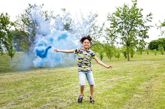 Joven arrastrando una bengala de humo azul en un parque