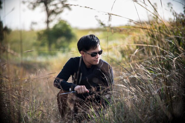 Joven arrodillado junto a las plantas en el campo