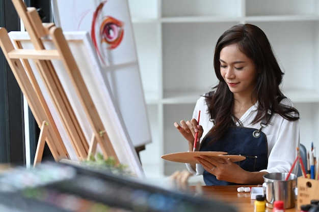 Joven artista asiática pintando un cuadro en su estudio