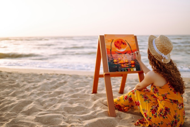 Joven artista dibujando la imagen en la playa Concepto de hobby y ocio