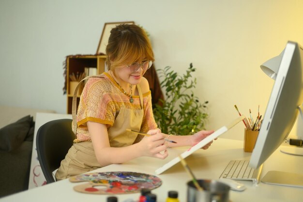 Una joven artista con gafas pintando en un lienzo en un acogedor estudio casero
