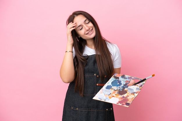 Joven artista mujer ucraniana sosteniendo una paleta aislada sobre fondo oink riendo