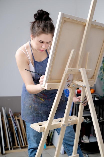 Una joven artista pinta un cuadro con aceite en lienzo en un estudio de arte
