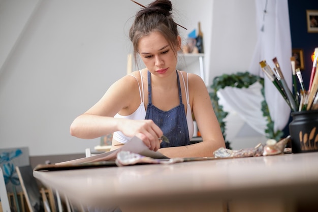 Una joven artista pinta un cuadro con aceite en lienzo en un estudio de arte