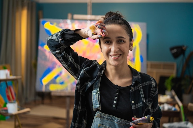 Foto joven artista profesional se frota la cara con la mano de la pintura pa tres en la cámara