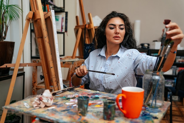 Joven artista trabajando en una pintura en el estudio.