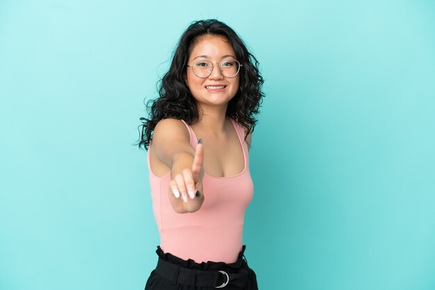 Joven asiática aislada sobre fondo azul mostrando y levantando un dedo