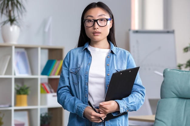 Joven asiática con anteojos secretaria asistente interna por primera vez en un lugar de trabajo en el