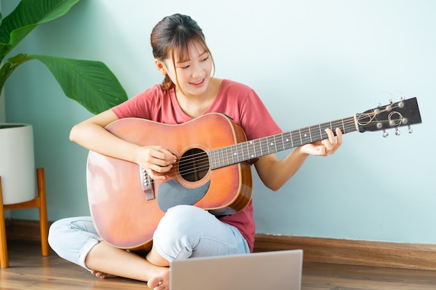 Joven asiática aprendiendo guitarra en casa