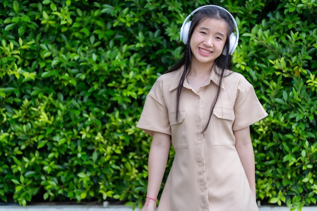 Foto joven asiática con auriculares inalámbricos blancos y escuchando música