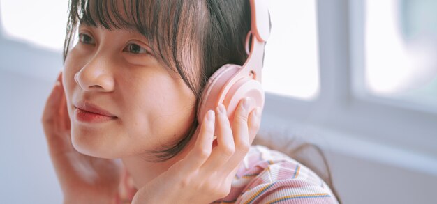 Joven asiática con auriculares inalámbricos para escuchar música