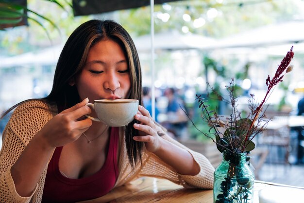 Joven asiática bebiendo café en una cafetería