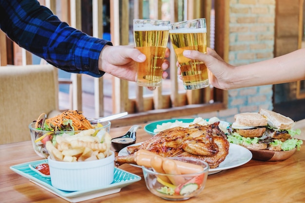 Joven asiática bebiendo cerveza y tintineo vasos felices mientras disfruta de fiesta en casa