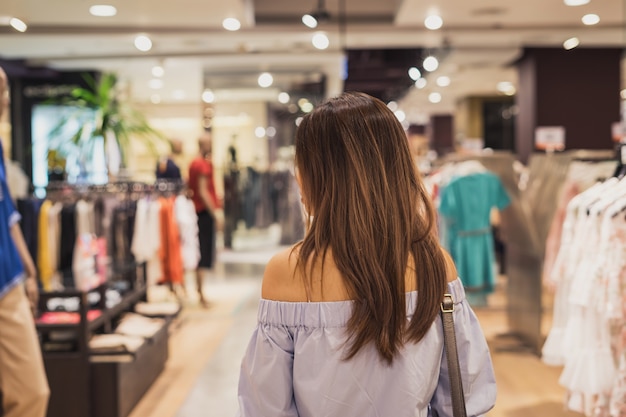 Joven asiática caminando en la tienda de ropa en el centro comercial