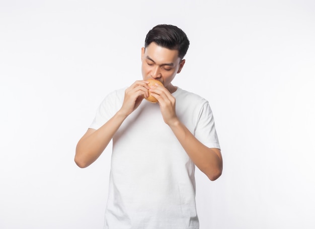Joven asiática en camiseta blanca comiendo hamburguesa