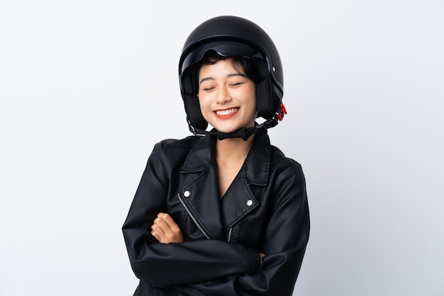 Joven asiática con un casco de moto sobre pared blanca aislada