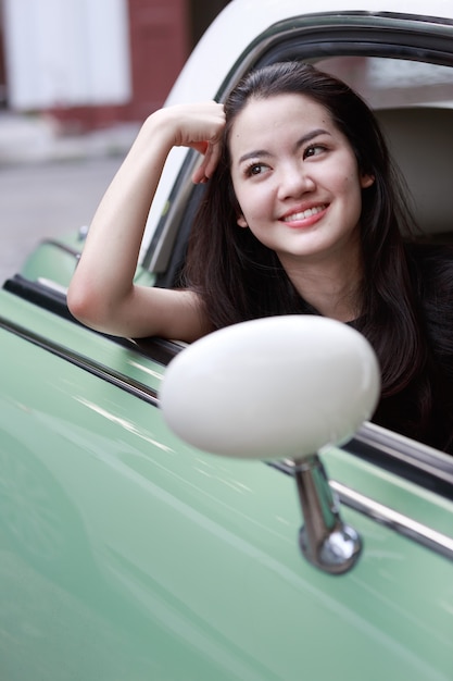 Joven asiática en un coche de época