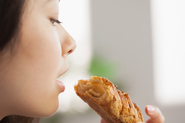 Joven asiática comiendo un pastel