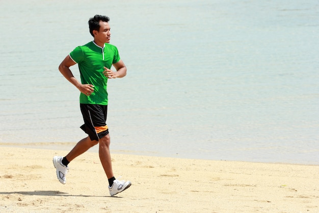 Joven asiática corriendo en la playa