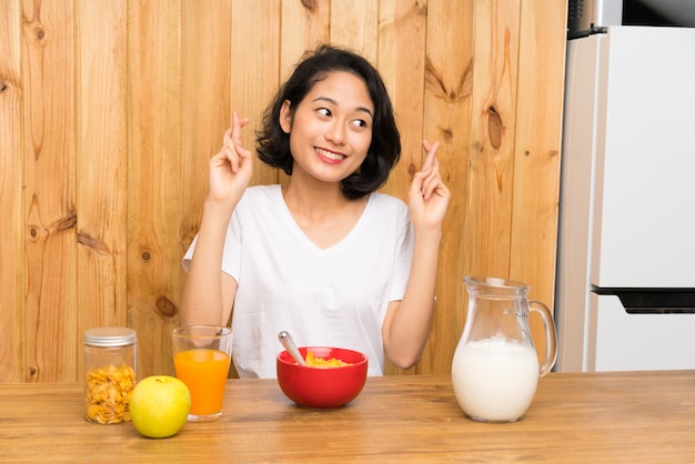 Joven asiática desayunando leche con cruzar los dedos