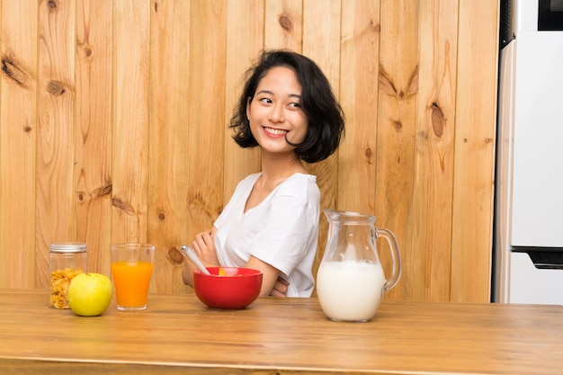 Joven asiática desayunando leche riendo