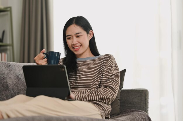 Una joven asiática despreocupada viendo videos en una tableta digital Gente tecnología y estilo de vida