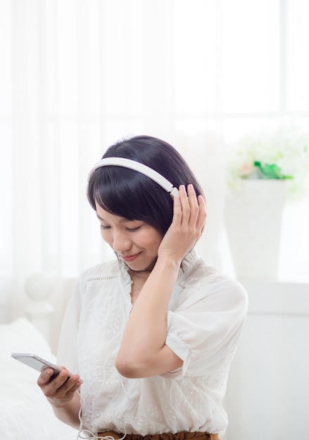 Joven asiática escuchando música en casa