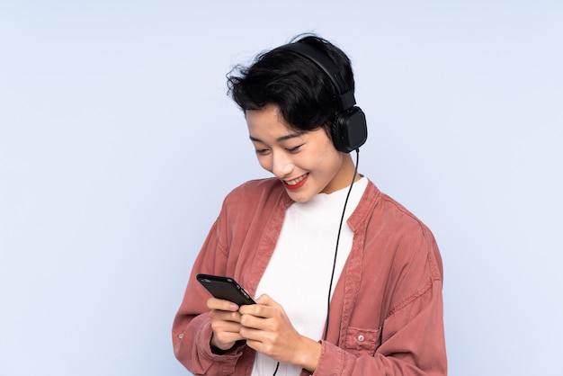 Joven asiática escuchando música y mirando al móvil