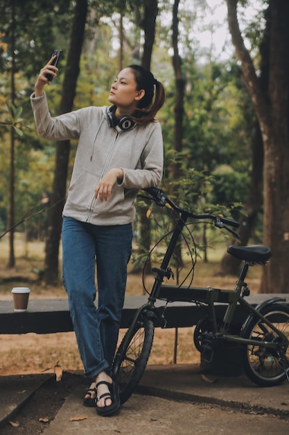 Una joven asiática feliz camina y anda en bicicleta en la calle del parque de la ciudad su sonrisa usando la bicicleta de transporte ecológico amigable concepto de estilo de vida de la gente