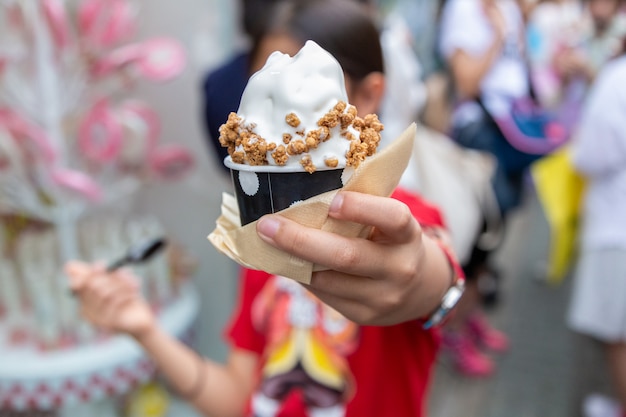Joven asiática feliz disfrutando de su crema suave, helado japonés, con cobertura de granola