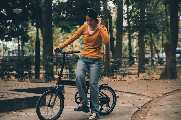 Una joven asiática feliz mientras andaba en bicicleta en un parque de la ciudad sonrió usando la bicicleta de transporte de concepto ecológico