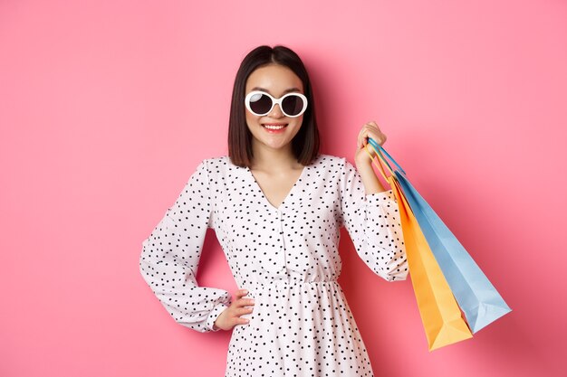 Joven asiática en gafas de sol ir de compras