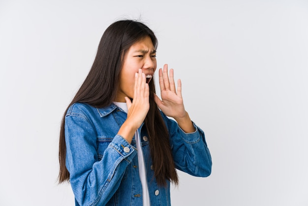 Joven asiática grita fuerte, mantiene los ojos abiertos y las manos tensas