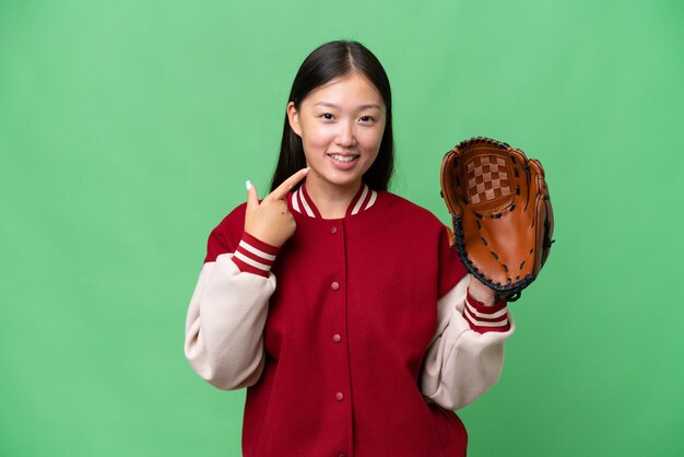 Joven asiática con guante de béisbol sobre un fondo aislado dando un gesto de pulgar hacia arriba