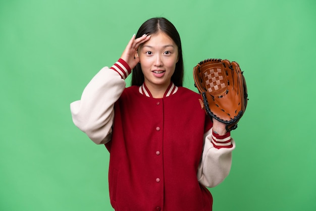 Joven asiática con guante de béisbol sobre un fondo aislado con expresión de sorpresa