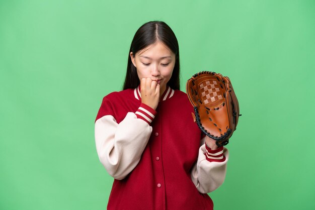 Joven asiática con guante de béisbol sobre un fondo aislado que tiene dudas