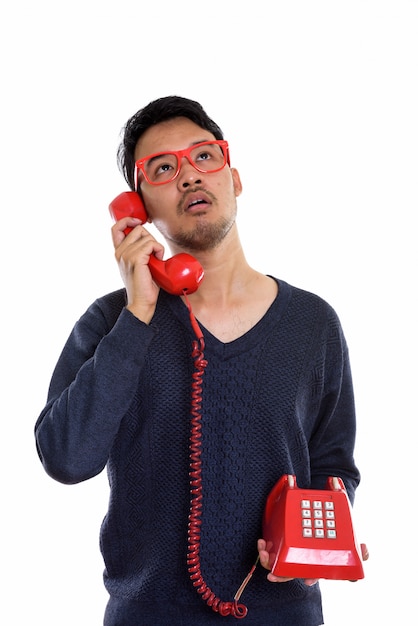 joven asiática hablando por teléfono antiguo mientras piensa