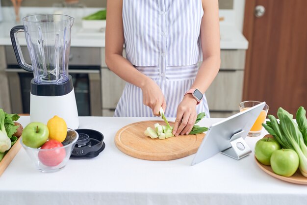 Joven asiática haciendo batidos de receta en tableta