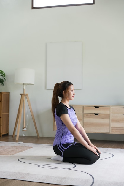 Joven asiática haciendo ejercicio de yoga vajrasana pose de diamante para entrenar un estilo de vida saludable en casa