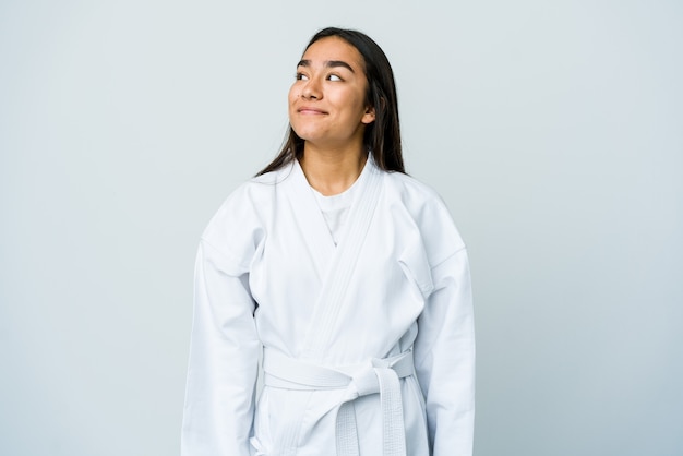 Foto joven asiática haciendo karate aislado en la pared blanca soñando con lograr metas y propósitos