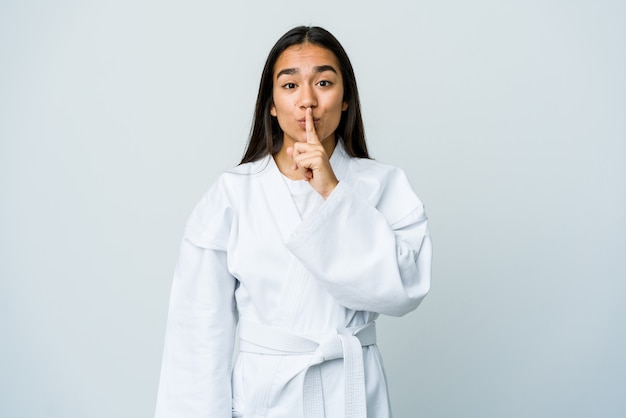 Joven asiática haciendo karate manteniendo un secreto o pidiendo silencio.