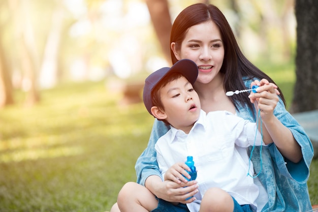 Joven asiática hermosa madre adolescente jugando con su hijo en el parque al aire libre