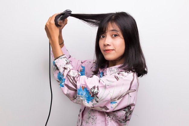 Joven asiática hermosa mujer feliz alisar el cabello con plancha de pelo sobre fondo blanco.