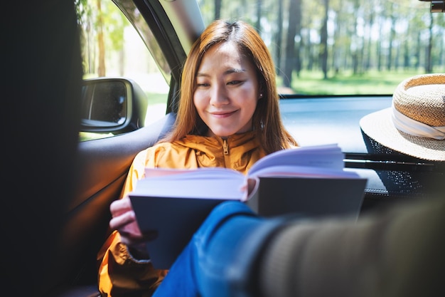 Una joven asiática leyendo un libro mientras viaja en el auto